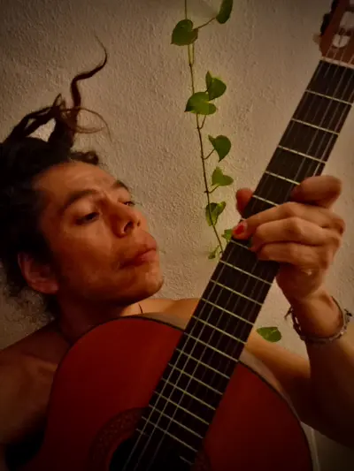 Acoustic guitar on a wooden stool in a warm studio setting